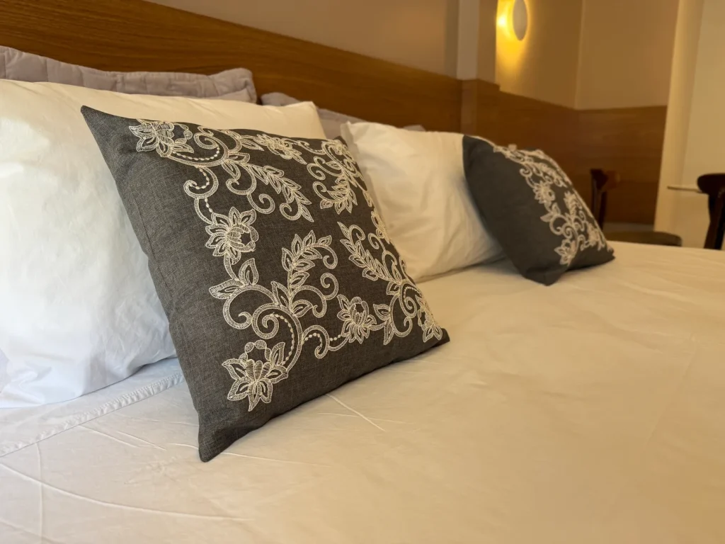 Detalhe das almofadas bordadas sobre a cama queen