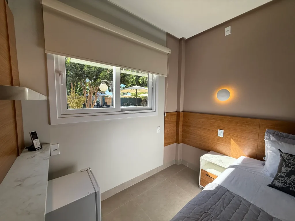 Janela do quarto com vista para o jardim, ao lado do frigobar