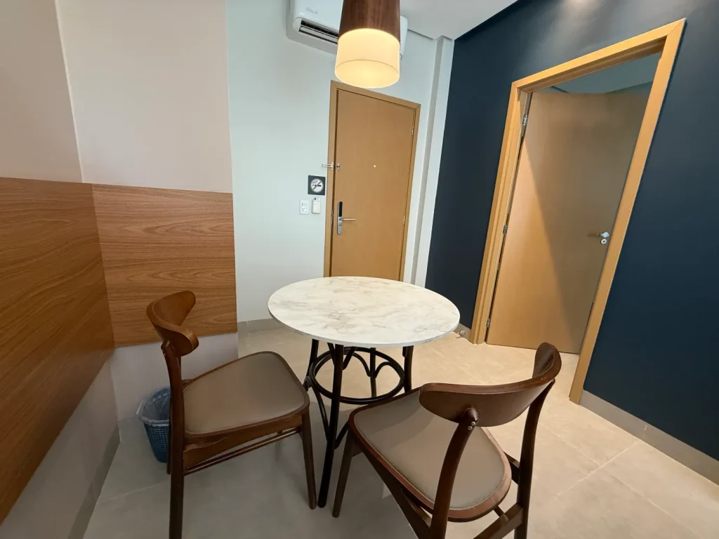 Mesa redonda com duas cadeiras junto à porta da suíte