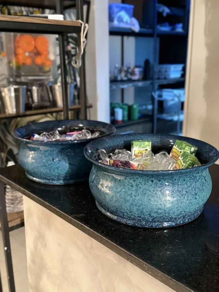 Dois bowls de cerâmica azul com caixinhas de suco sobre gelo.