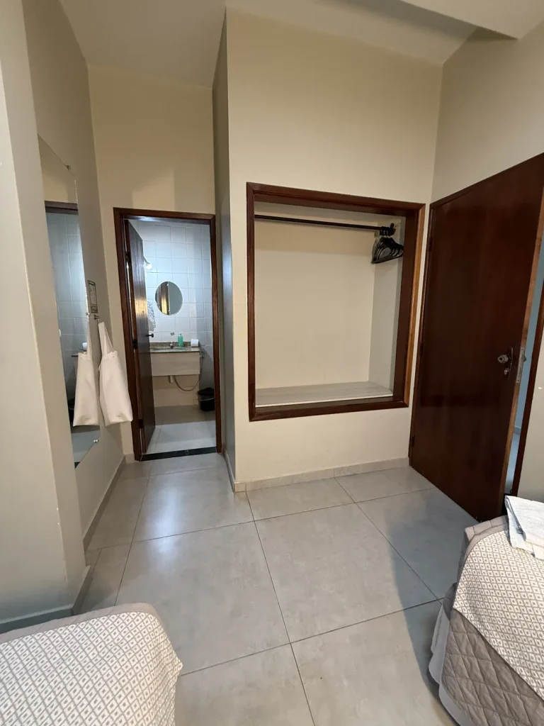 Entrada da suíte com armário embutido, espelho e porta do banheiro