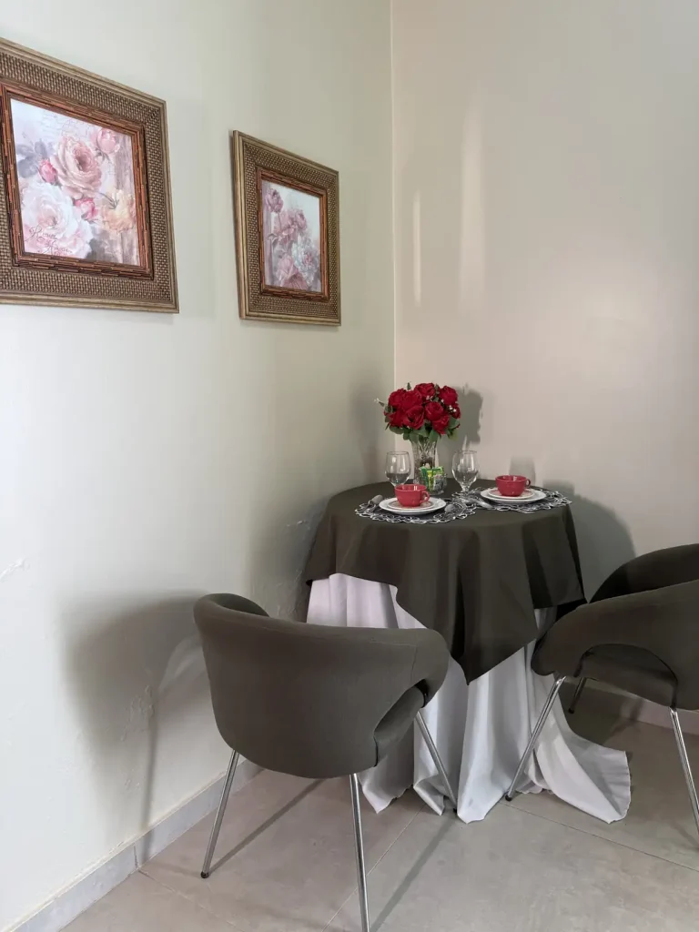 Mesa redonda com duas cadeiras, arranjo de rosas e quadros na parede