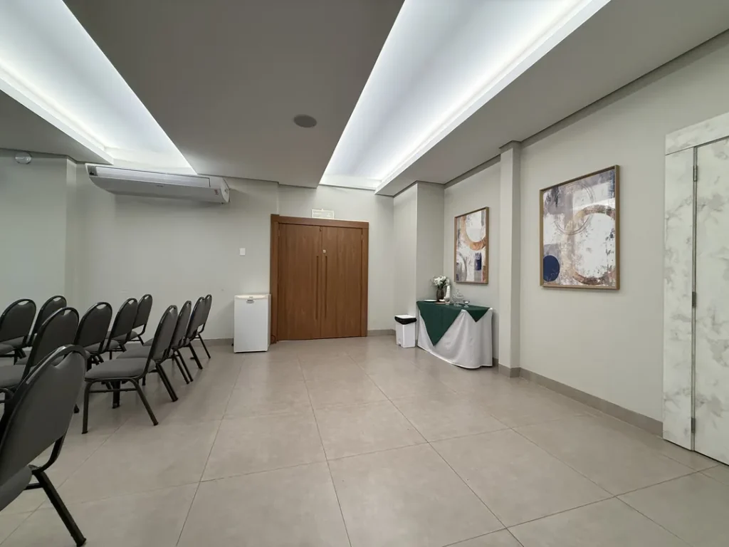 Porta de entrada do auditório com mesa de apoio de toalha verde e quadros na parede