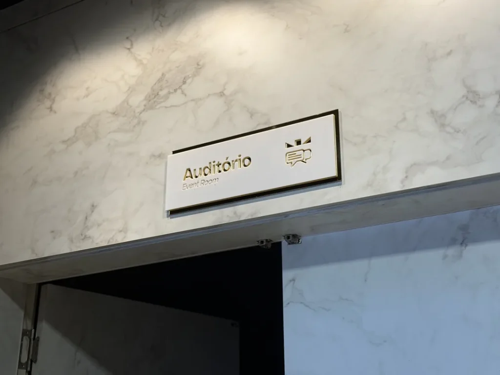 Placa do auditório sobre a porta, em parede revestida de mármore