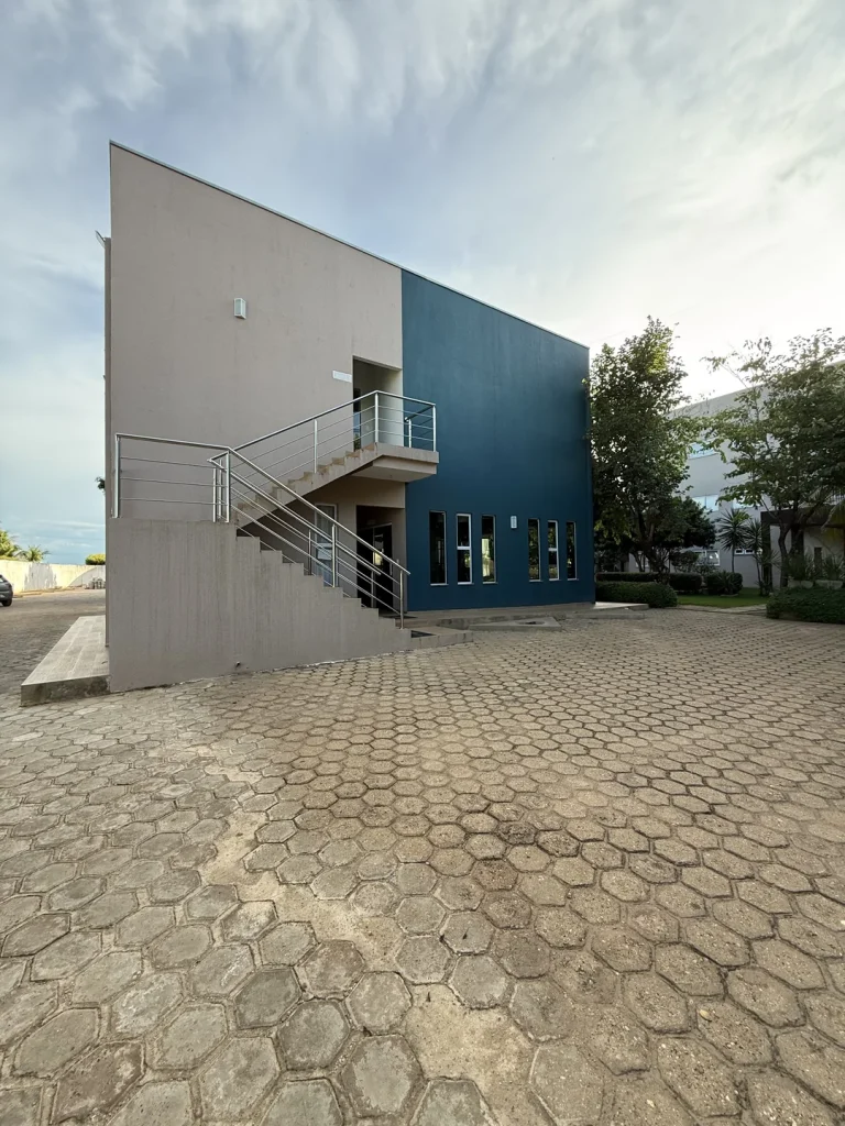 Prédio de dois andares com escada externa, junto ao pátio de piso intertravado