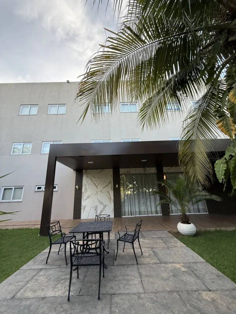 Entrada coberta com mesa e cadeiras de ferro sobre o gramado